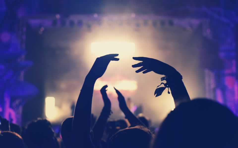 Hands raised in a crowd in front of a lit festival stage